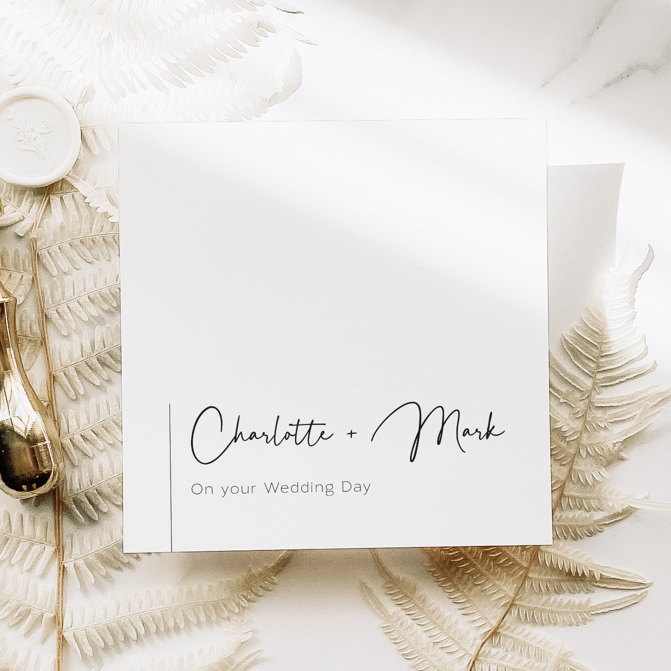 Wedding card with 'Charlotte + Mark' on a decorative background with leaves and a vase.