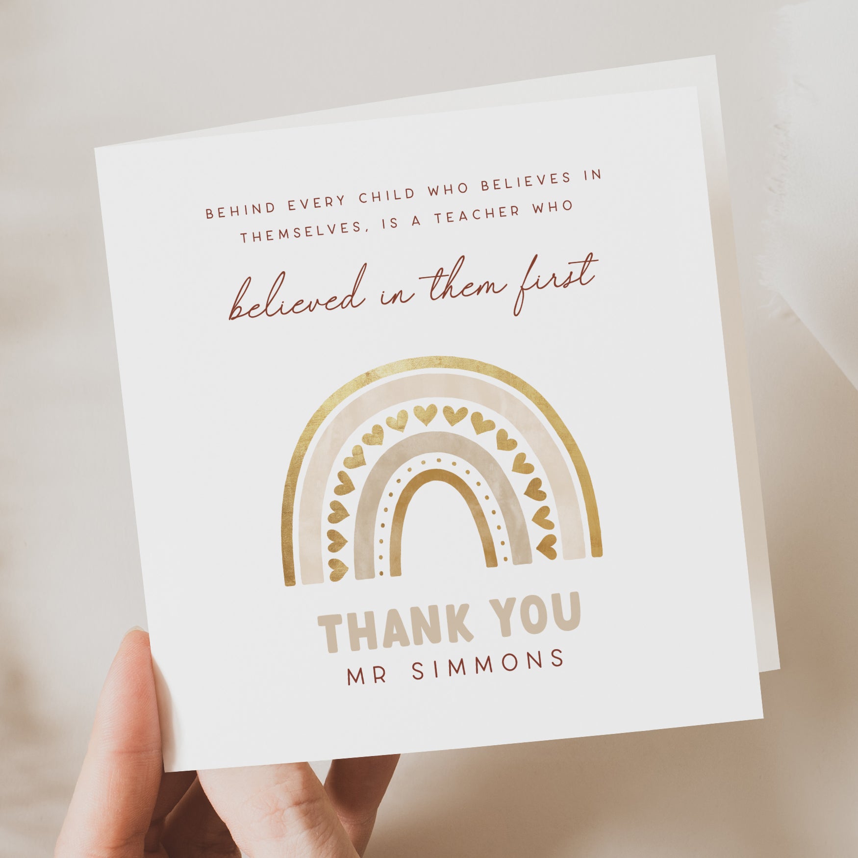 Card with rainbow design and text held by a hand on a neutral background