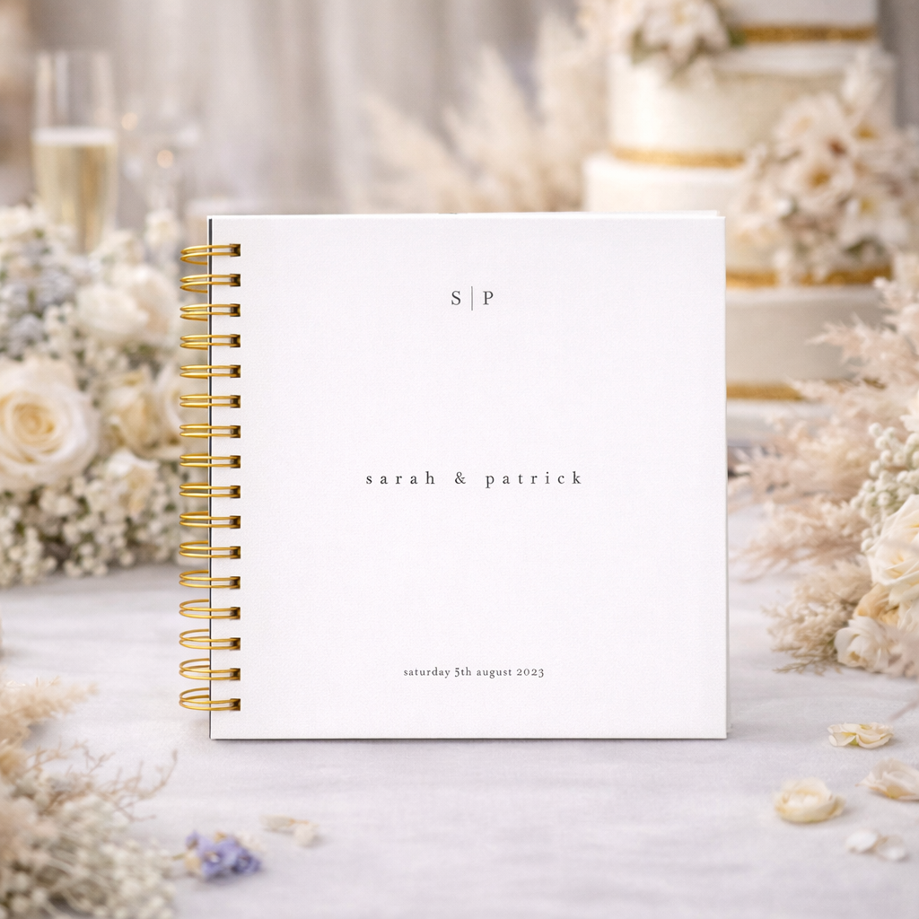 White wedding guest book with gold binder on wedding table with champagne flowers
