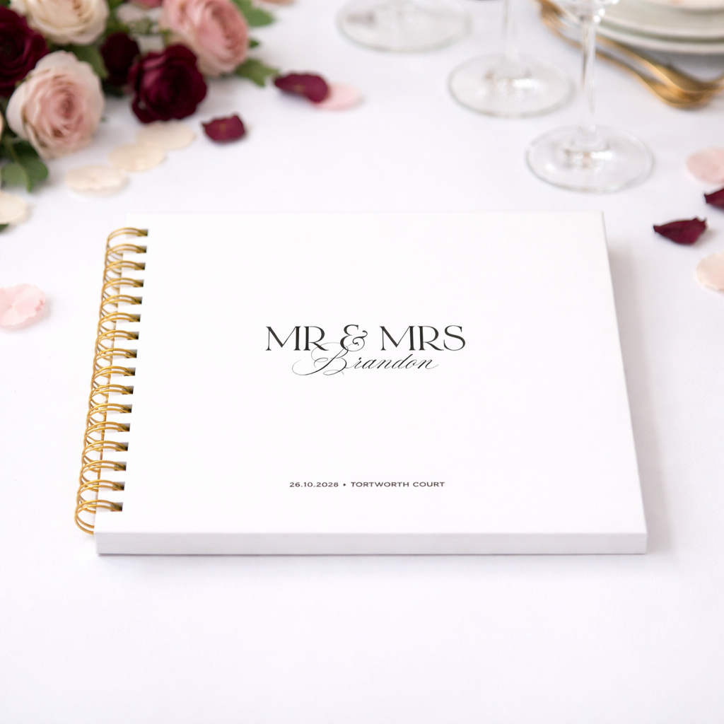 Personalised planner with 'MR & MRS Brandon' on a decorative table with flowers and glasses.