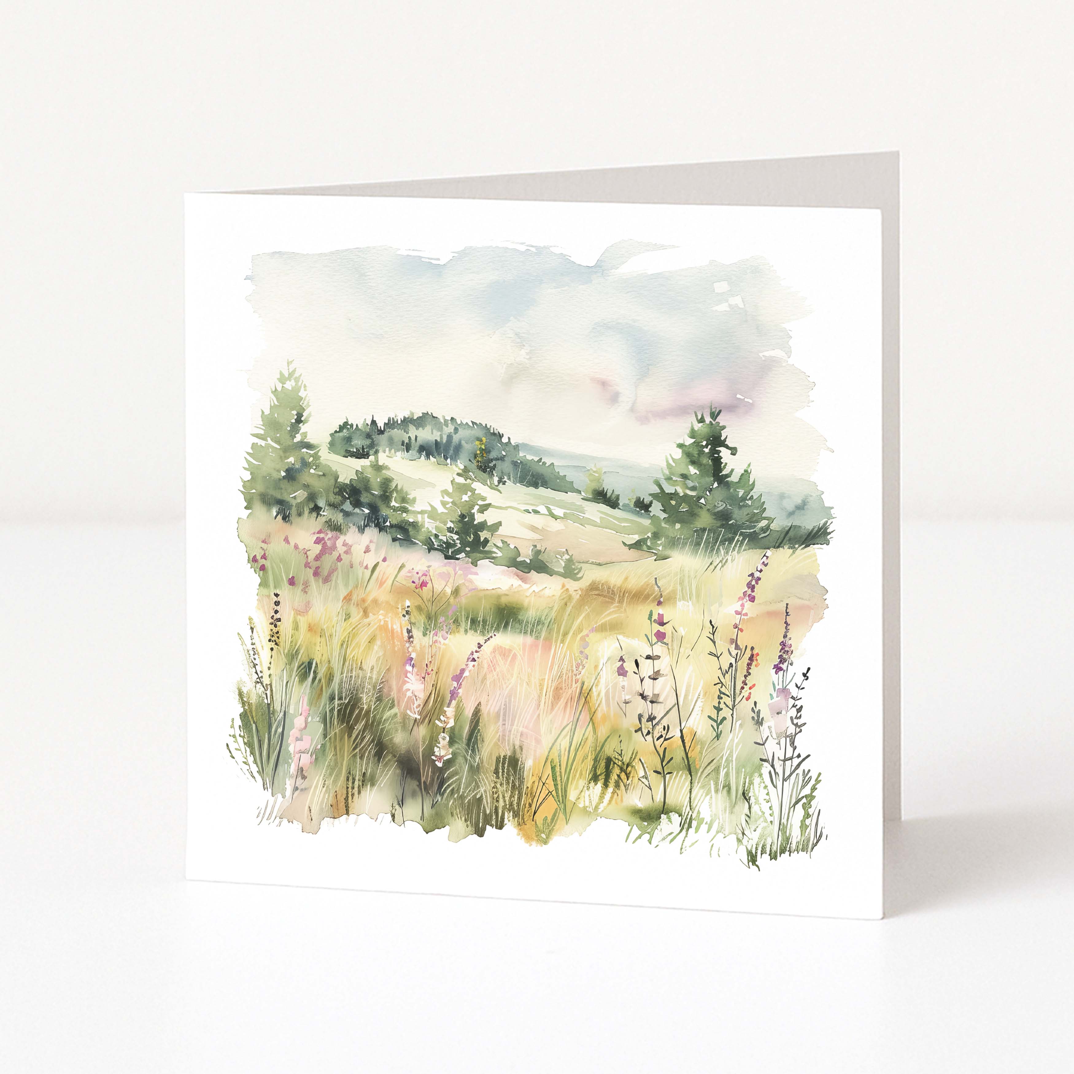 Greeting card with a watercolor landscape of a field and trees on a white background