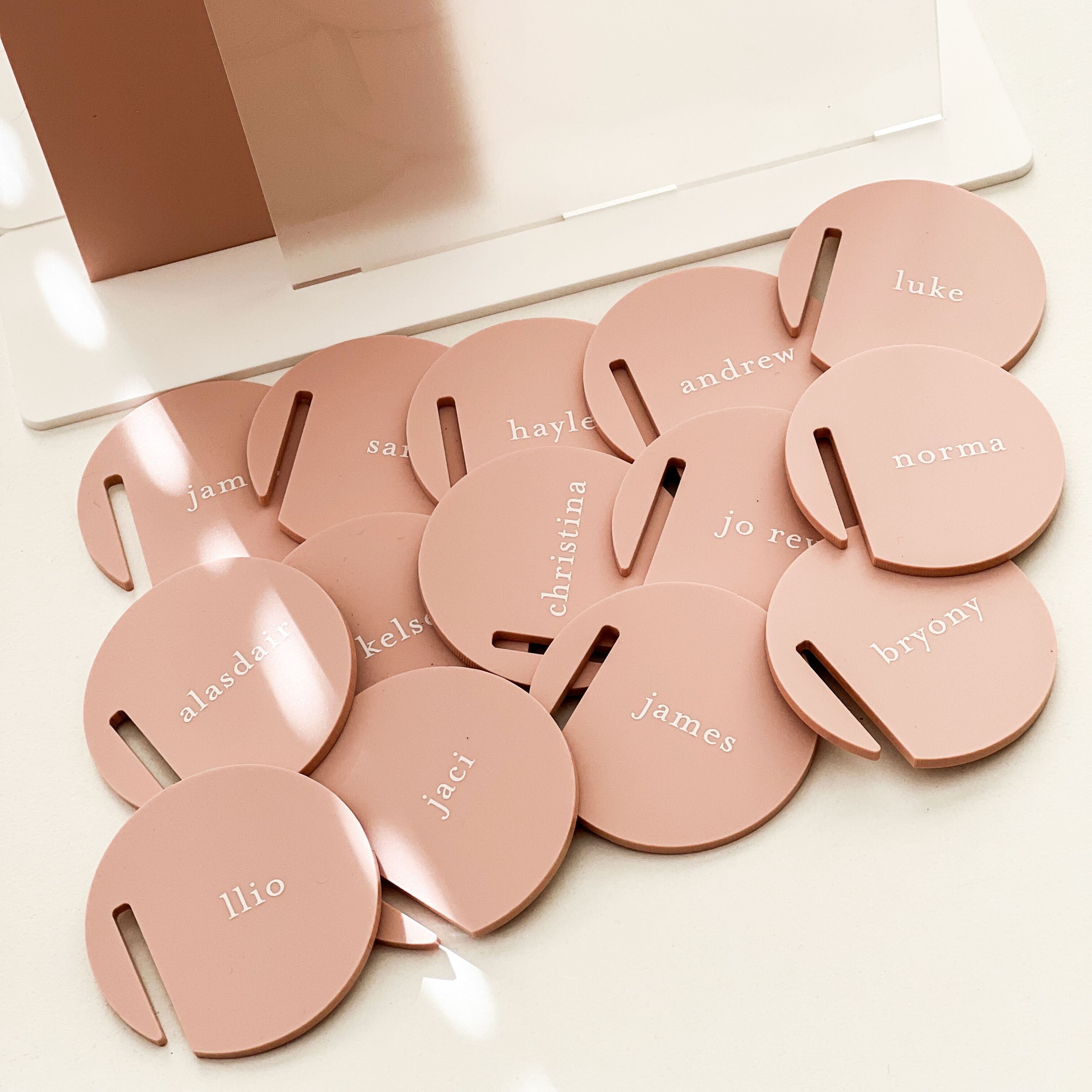 Set of pink name tags with names engraved on them, placed on a white surface.