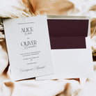 Wedding invitation card with a dark purple envelope on a textured surface