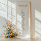 Cotton and linen wedding seating plan hanging on a stand with floral arrangement