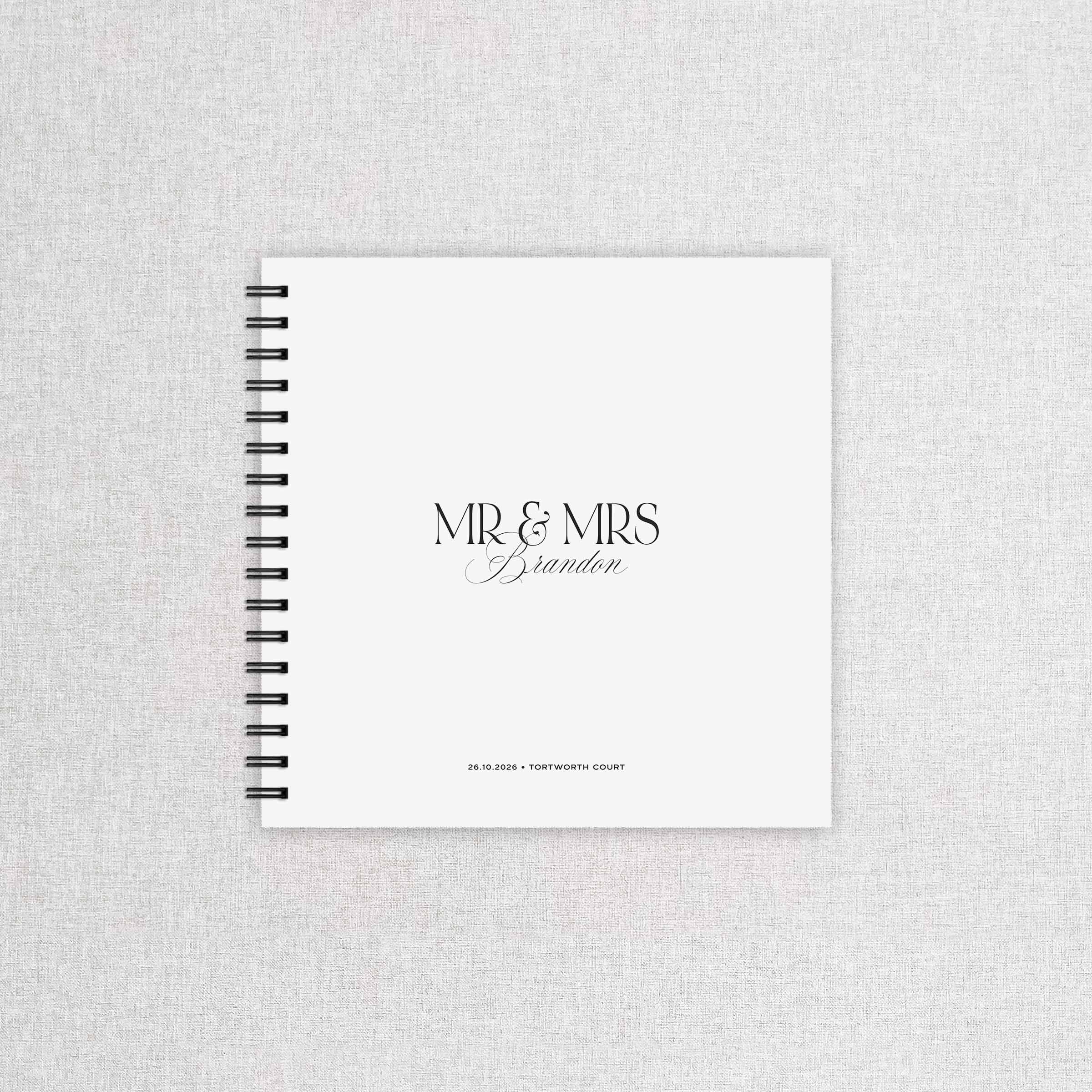 Spiral-bound wedding guest book with 'MR & MRS Brandon' text on a textured gray background