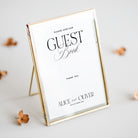 Gold-framed sign for guest book with personalized text on a light background