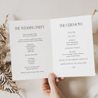 Wedding ceremony program held by a hand with dried leaves on a light background