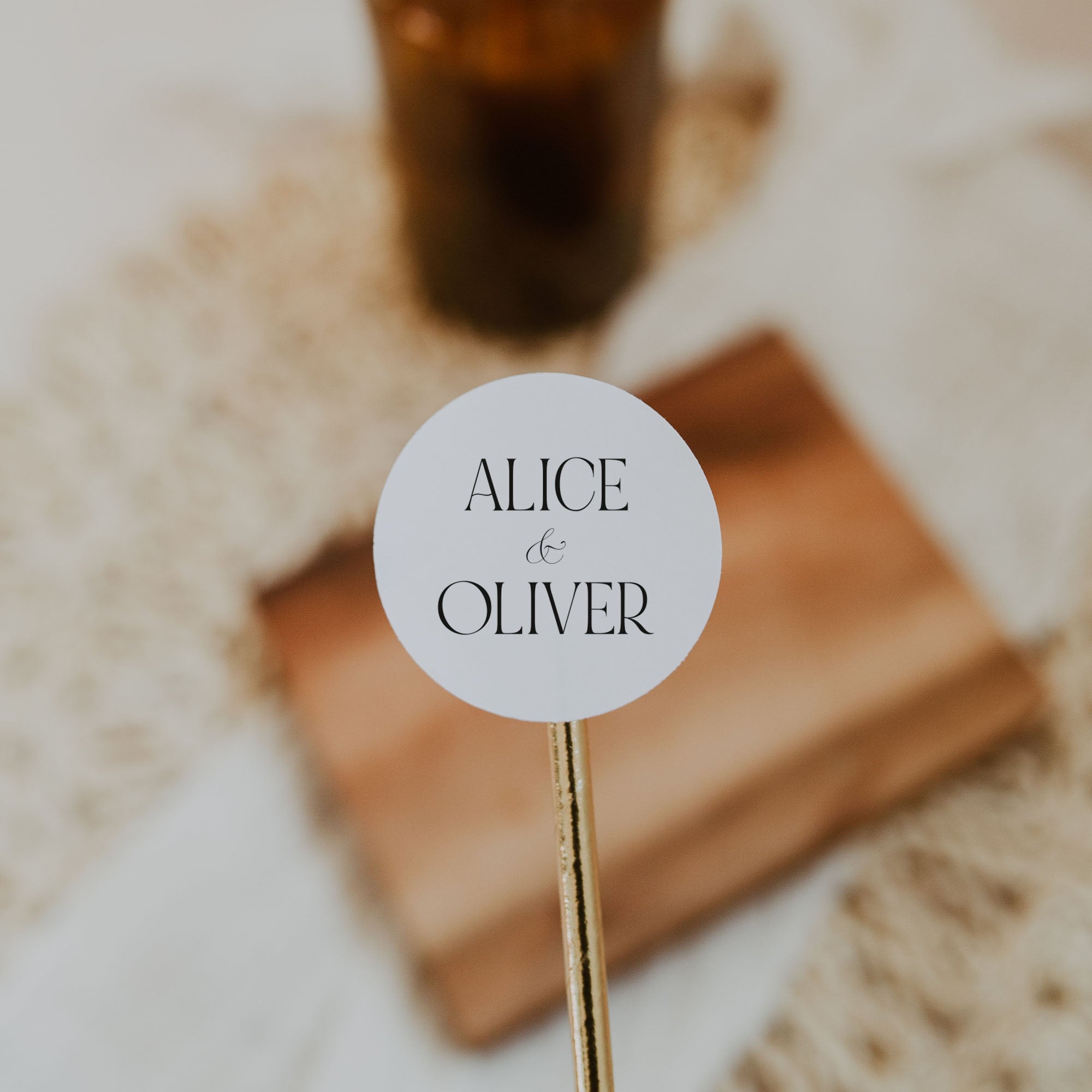 Round label with 'Alice & Oliver' text on a stick, blurred background