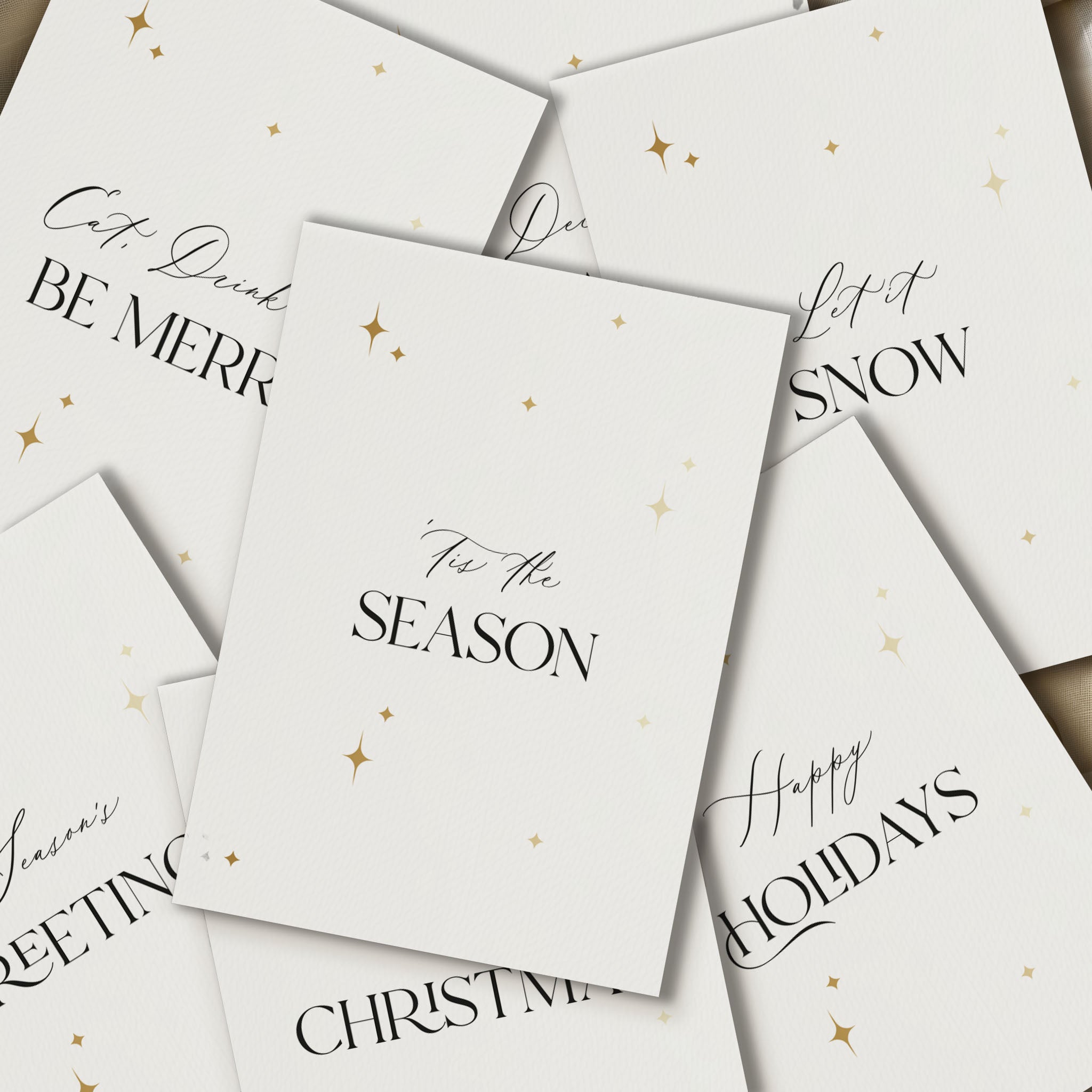 Stack of white Christmas cards with black text and gold stars on a white background