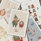 Collection of Christmas-themed greeting cards with various designs including a bear, hedgehog, snowman, and floral elements.