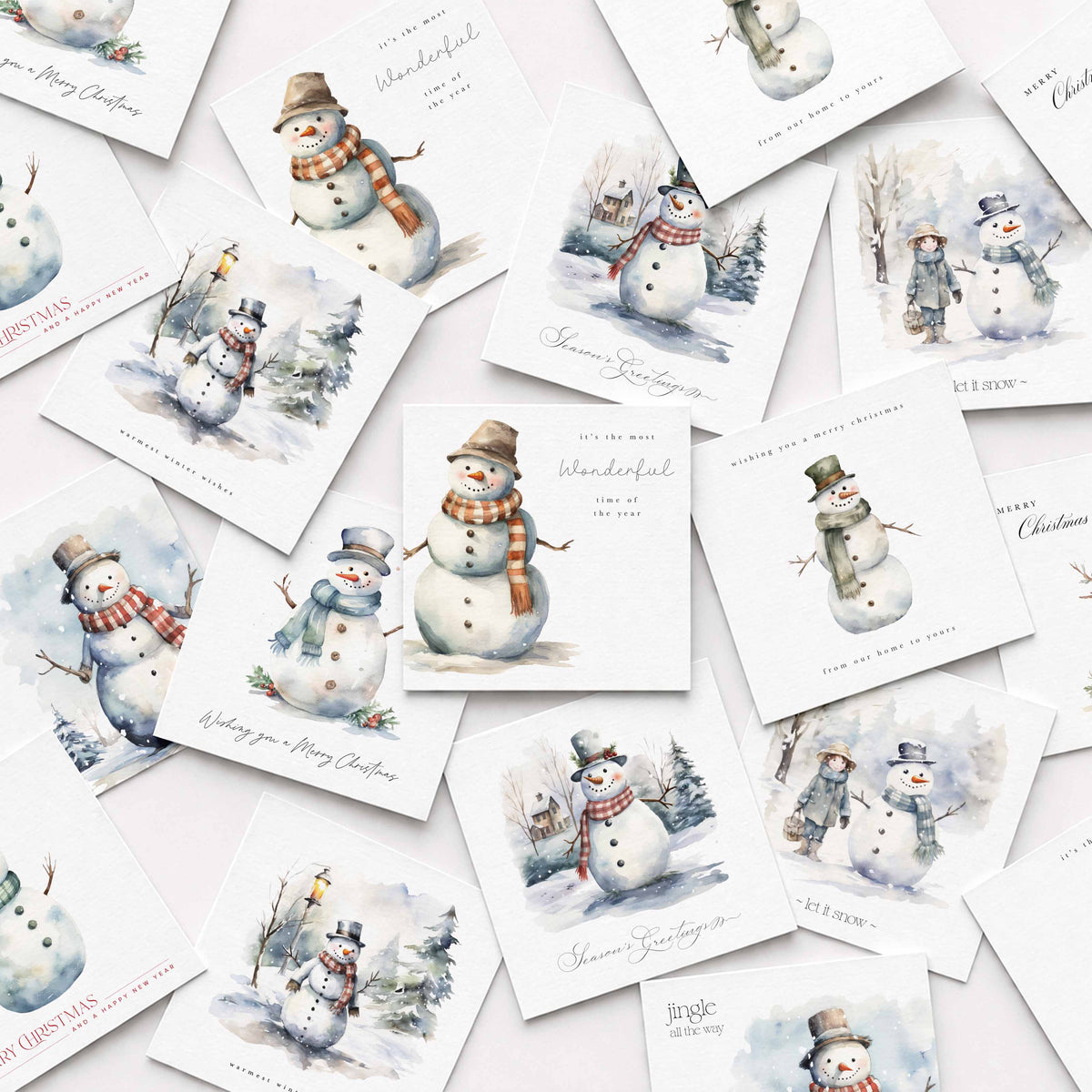 A scattered arrangement of square Christmas greeting cards featuring watercolor illustrations of snowmen in winter scenes, with phrases like 'Merry you a Happy Christmas' and 'Wonderful Christmas.'.