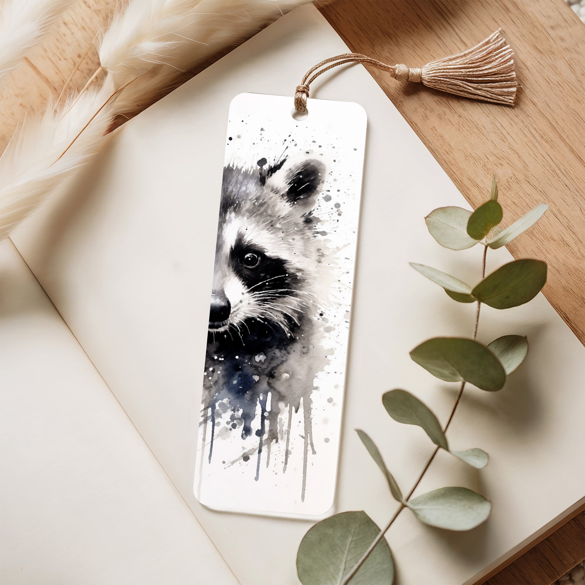 ACrylic Bookmark with raccoon design on a wooden surface with eucalyptus leaves