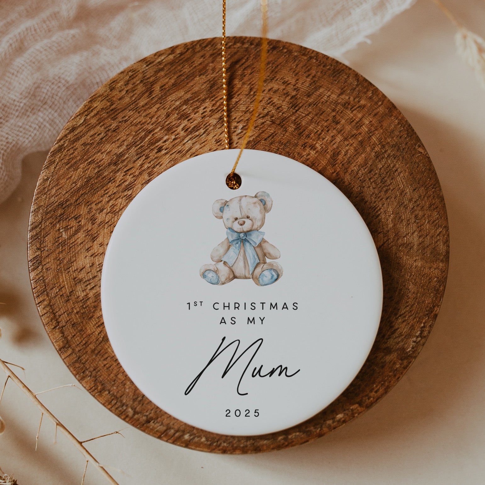 Decorative ornament with a teddy bear and text on a wooden circle, hanging against a soft background.