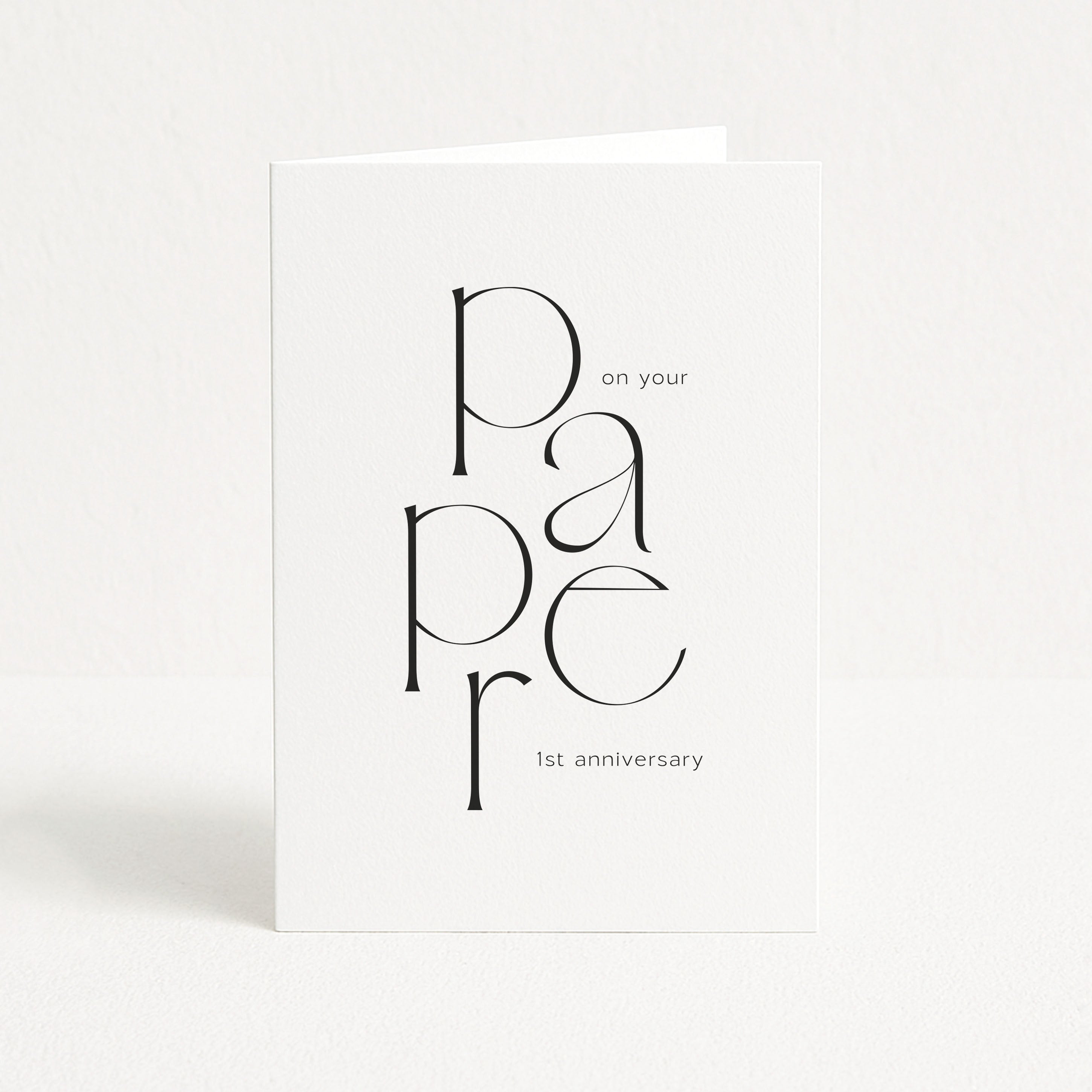 White card with black text 'p a p e r on your paper 1st anniversary' on a white background