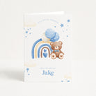 Greeting card with a teddy bear, rainbow, and balloons on a white background