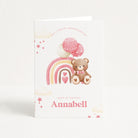 Birthday card with a teddy bear, rainbow, and balloons on a white background