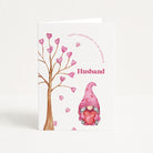 Greeting card with a gnome holding a heart and a tree with hearts, labeled 'Happy Anniversary to my gorgeous Husband'.