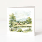 Greeting card with a watercolor landscape of trees, house, and lake on a white background