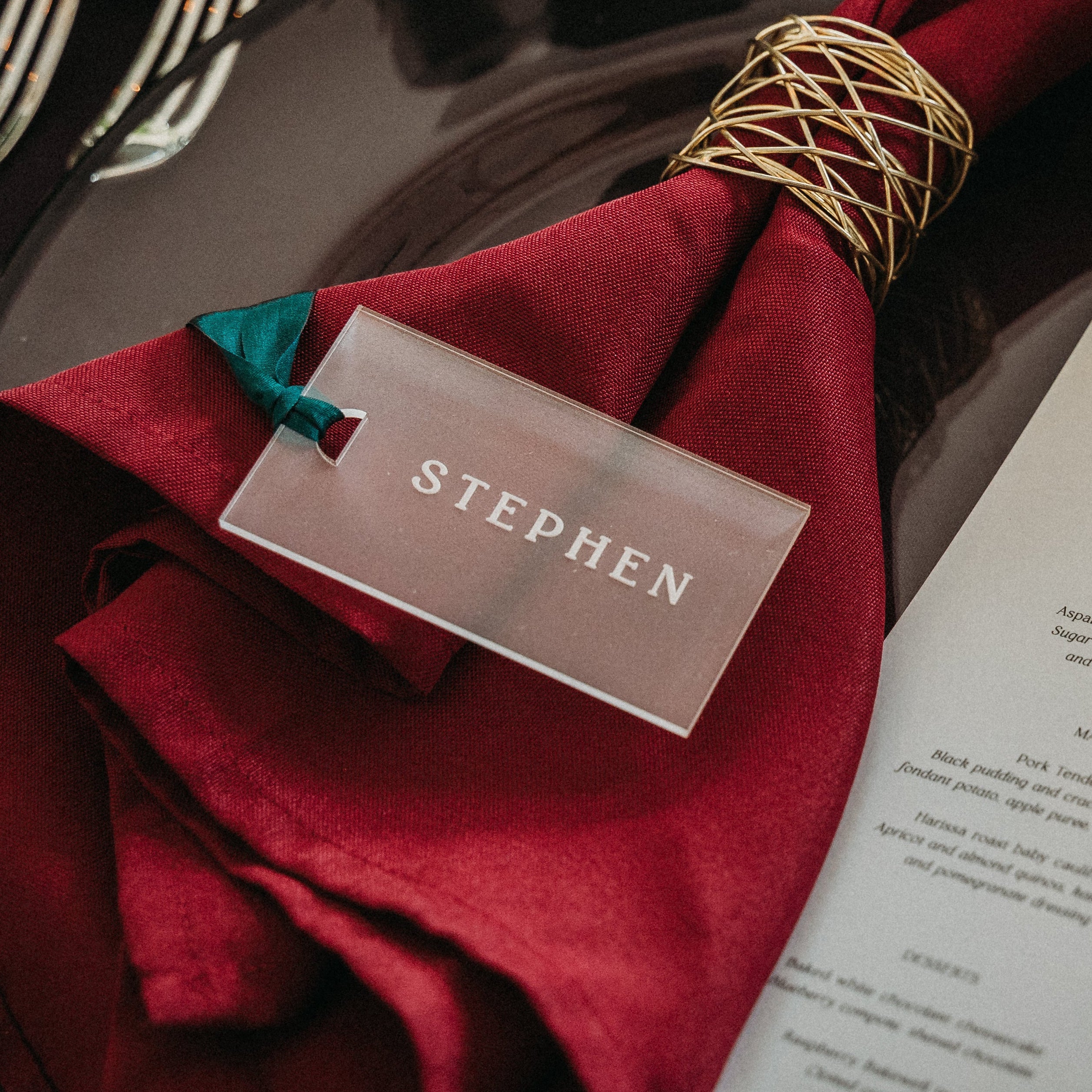 frosted acrylic place card with guest name and silk green ribbon