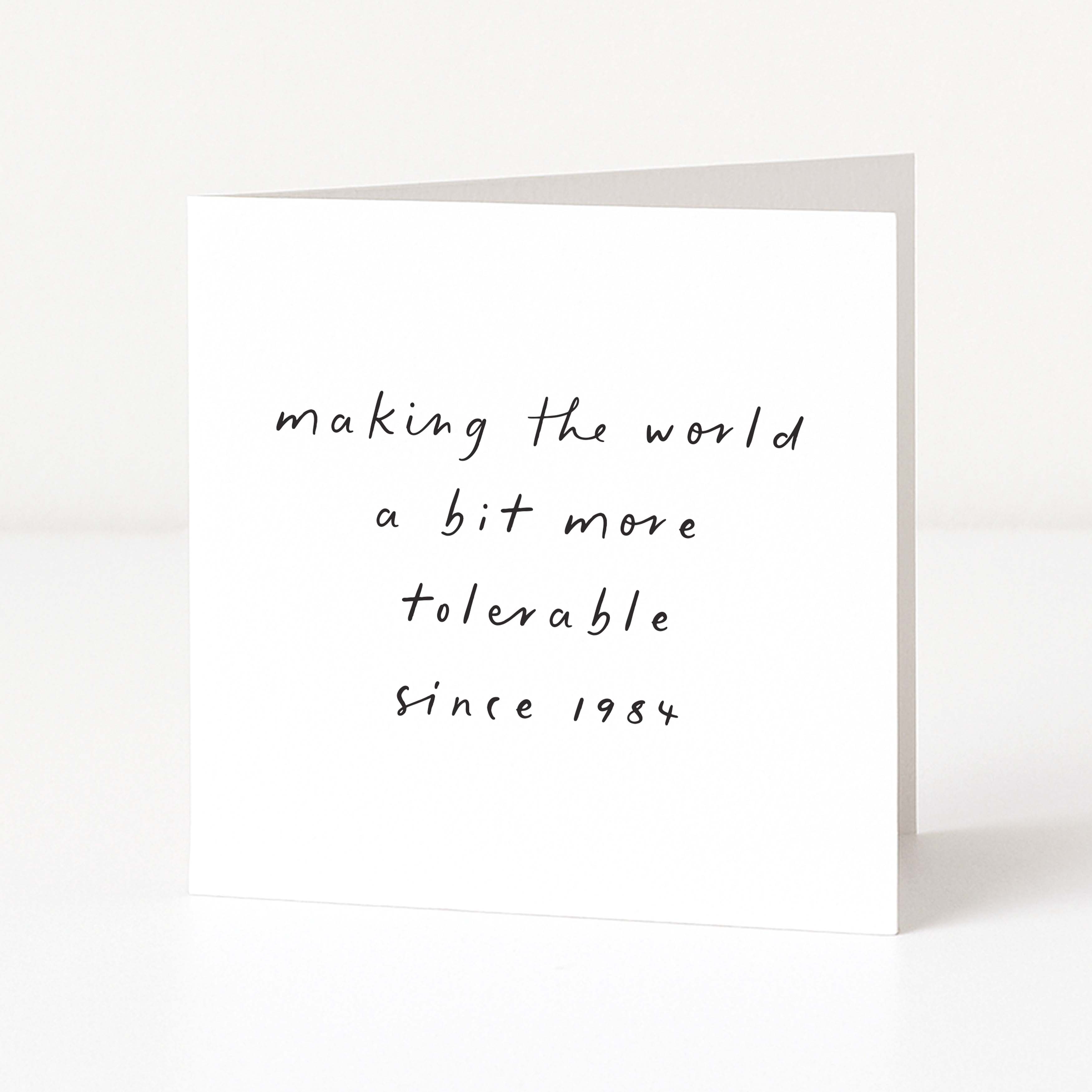 White card with black text 'making the world a bit more tolerable since 1984' on a white background