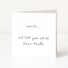 White card with black text 'smile... whilst you still have teeth' on a white background