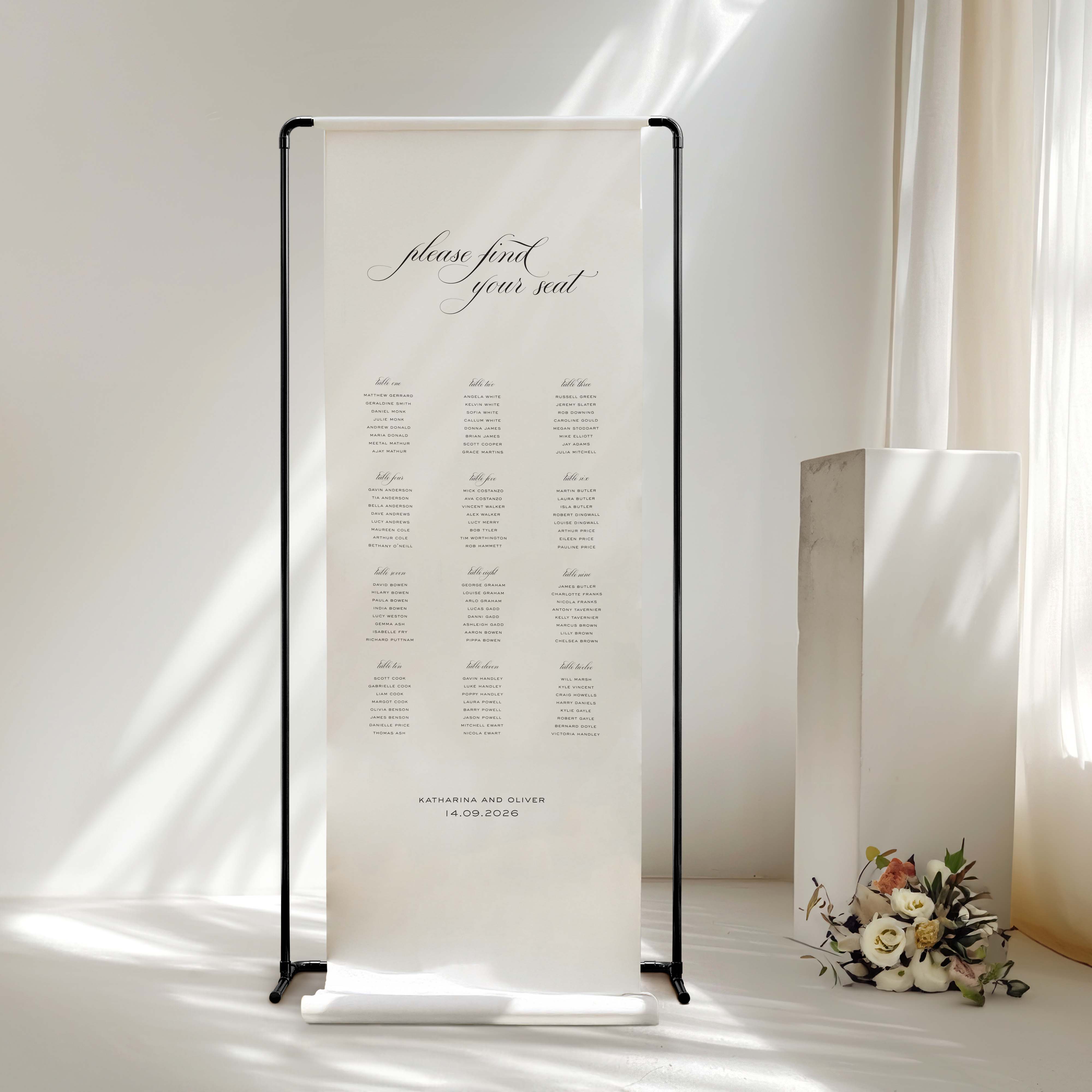White banner with text on a black stand next to a bouquet of flowers in a softly lit room.