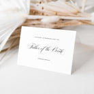 Reserved seat card for the Father of the Bride on a white surface with dried plants in the background