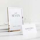 Table number and place card on a white surface with a gold frame