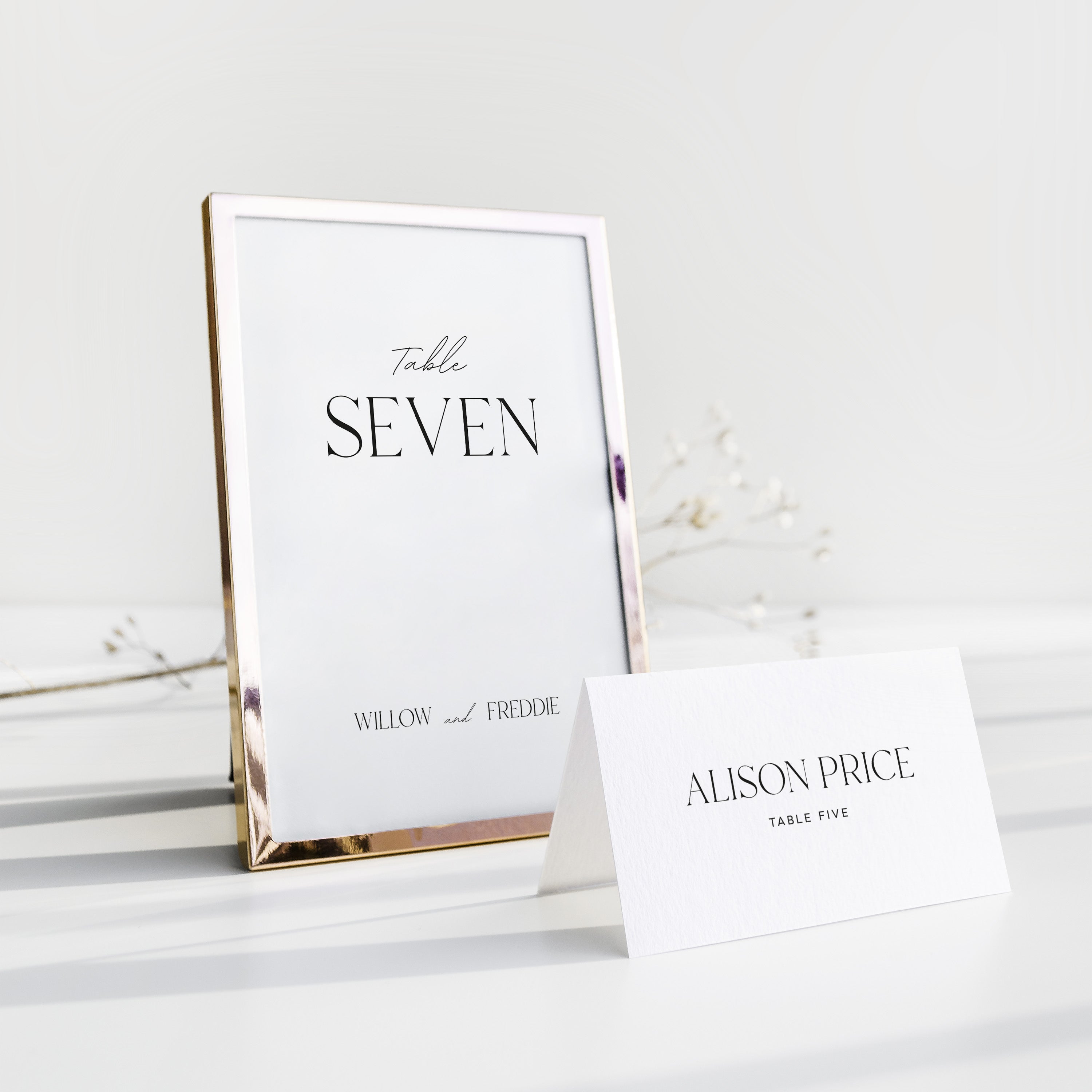 Table number and place card on a white surface with a gold frame