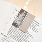 Open book with a decorative card on a wooden surface