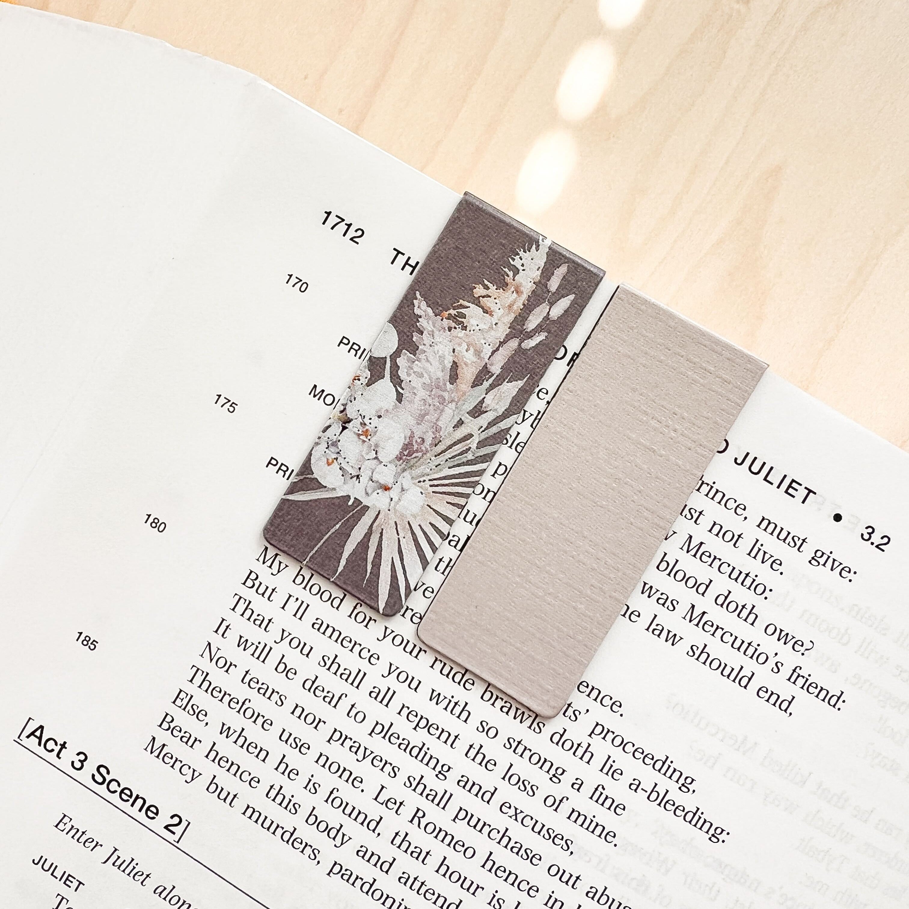 Open book with a decorative card on a wooden surface