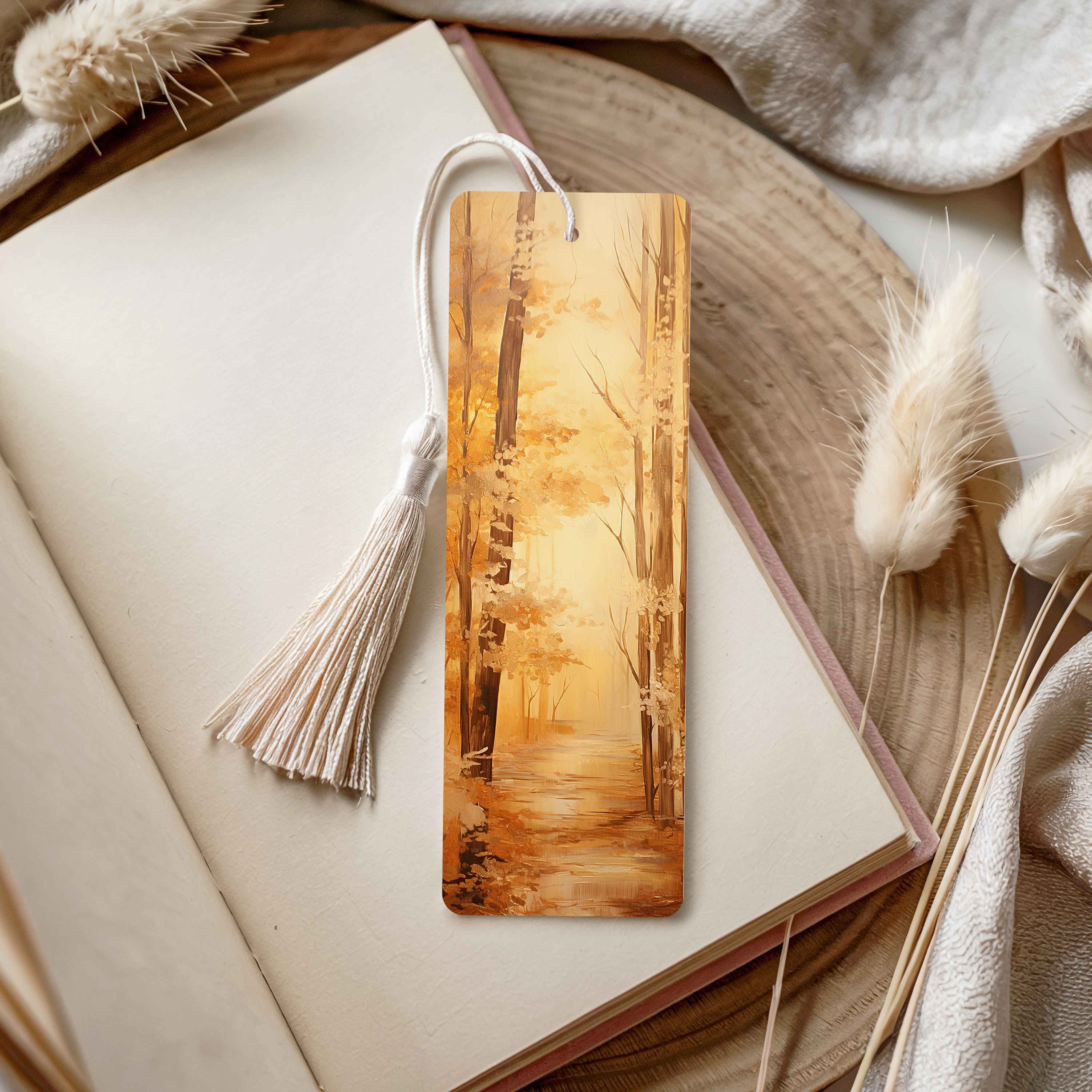 Acrylic bookmark with tassel on an open book, surrounded by dried plants and soft fabric