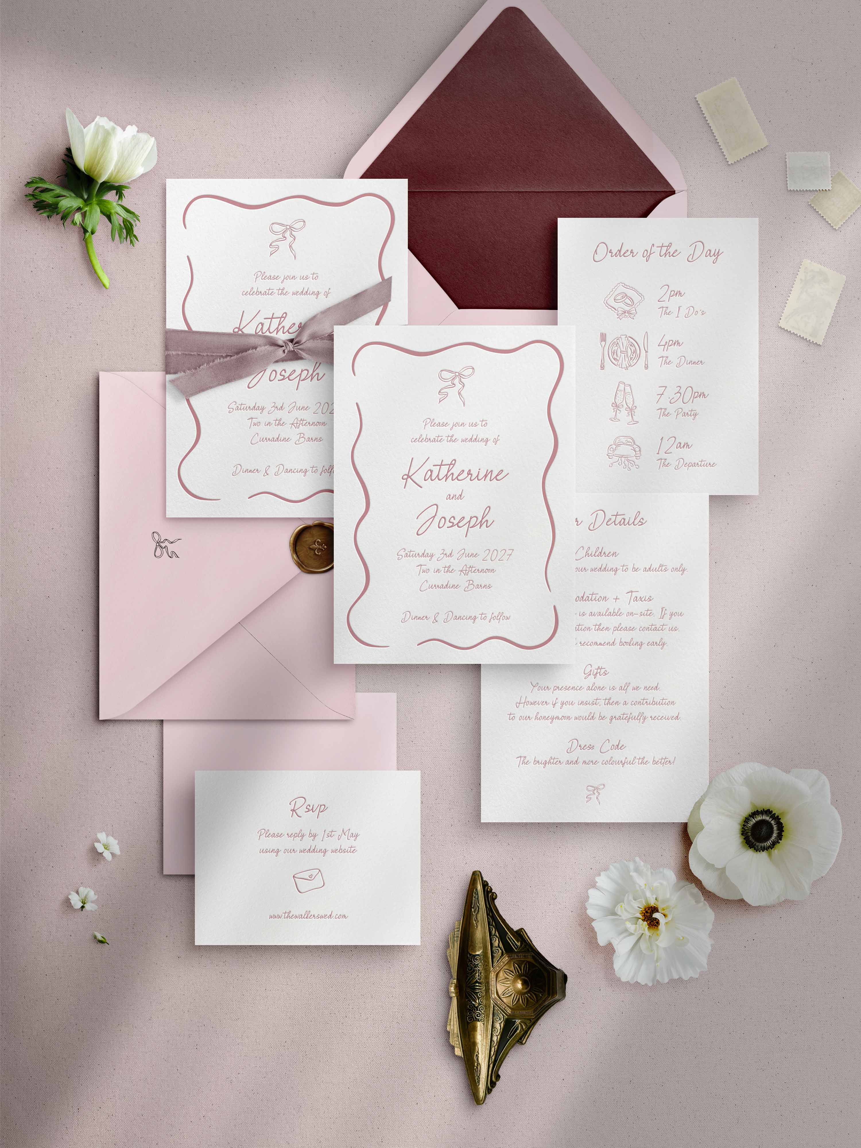 A flat lay of a letterpress wedding invitation suite in a white and pink colour scheme