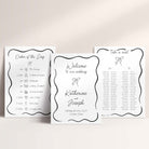 Three wedding signage boards arranged on a light beige background. The centre reads 'Welcome to our wedding' with the names Katherine and Joseph and the date Saturday, 26 June 2027, while the side cards show 'Order of the Day' and 'Take a seat' with black decorative borders and small illustrations.