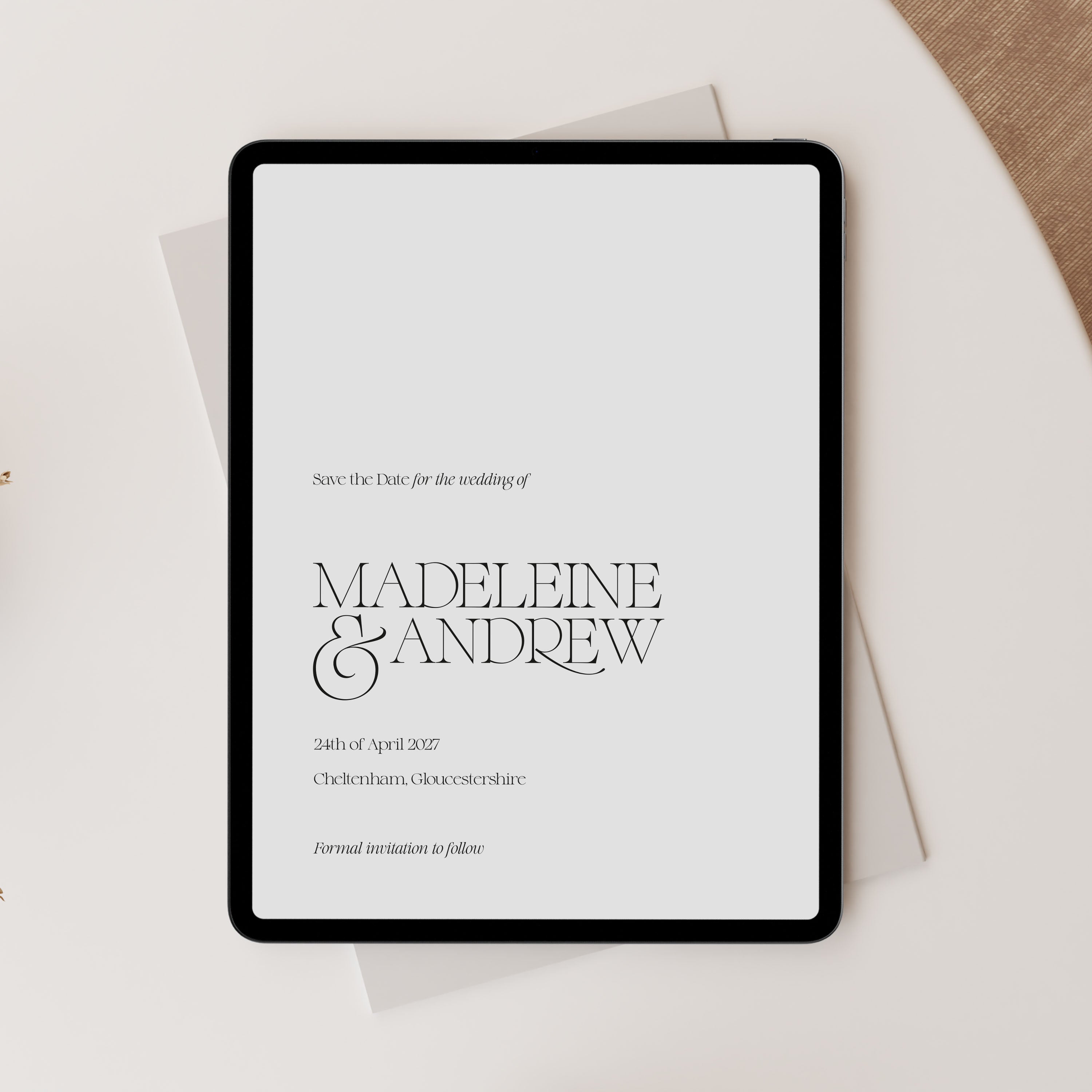 Digital tablet displaying a wedding save-the-date invitation with 'Madeleine & Andrew' on a light background.