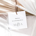 White card with 'Thank you for celebrating with us M & A' text, hanging on dried palm leaves.