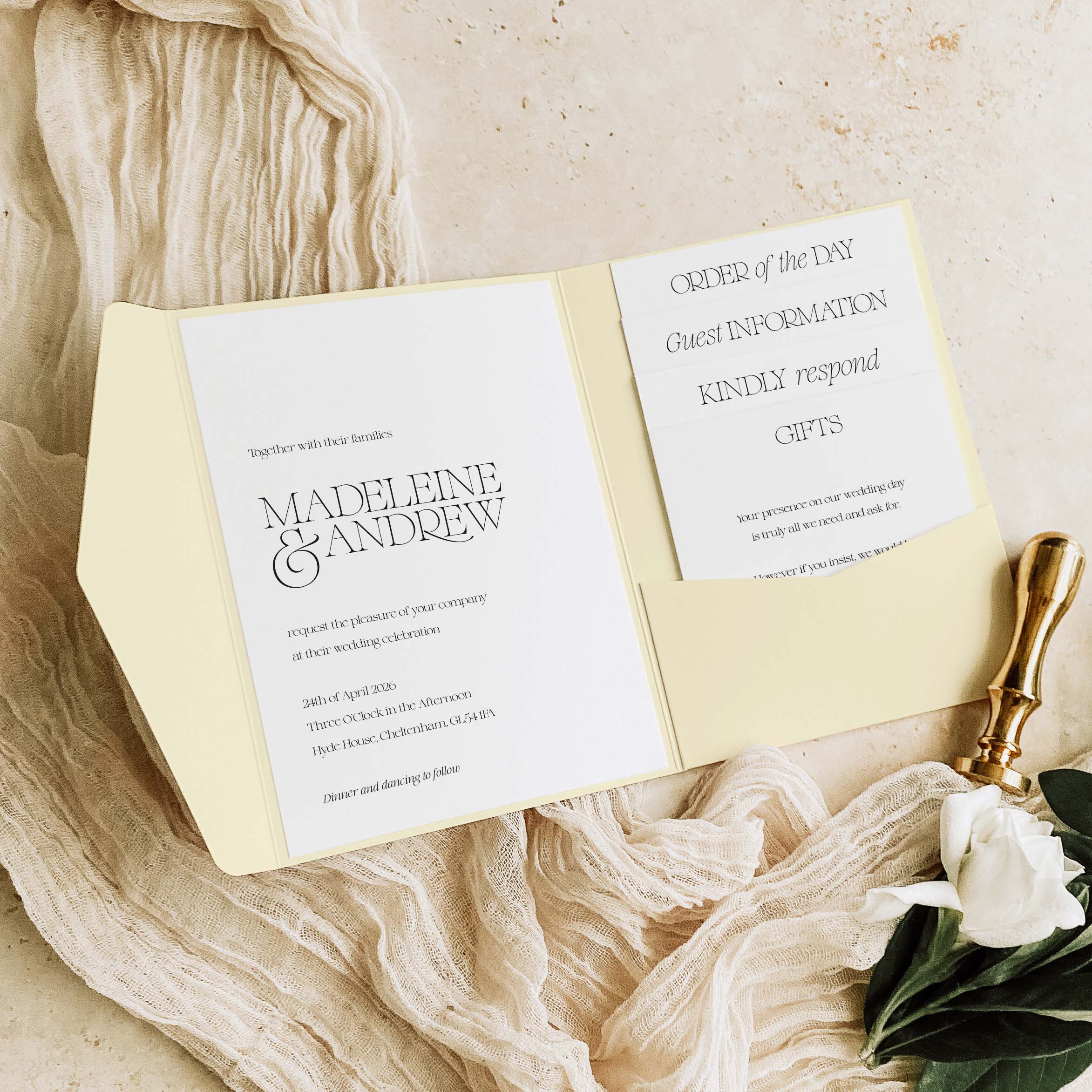 Pocketfold Wedding invitation set with gold wax stamp on a textured beige surface