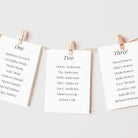 Individual table plan cards for a wedding hanging from a string with pegs