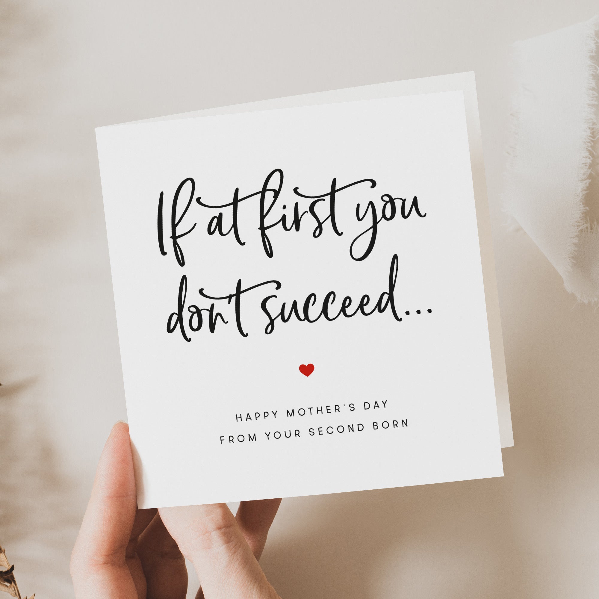 Hand holding a card with a Mother's Day message on a soft beige background