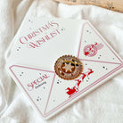 White envelope with red text and design, featuring a gold stamp on a white fabric background.