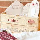 Wooden Christmas Eve gift box with personalised name 'Chloe' and Christmas-themed items on a soft surface.