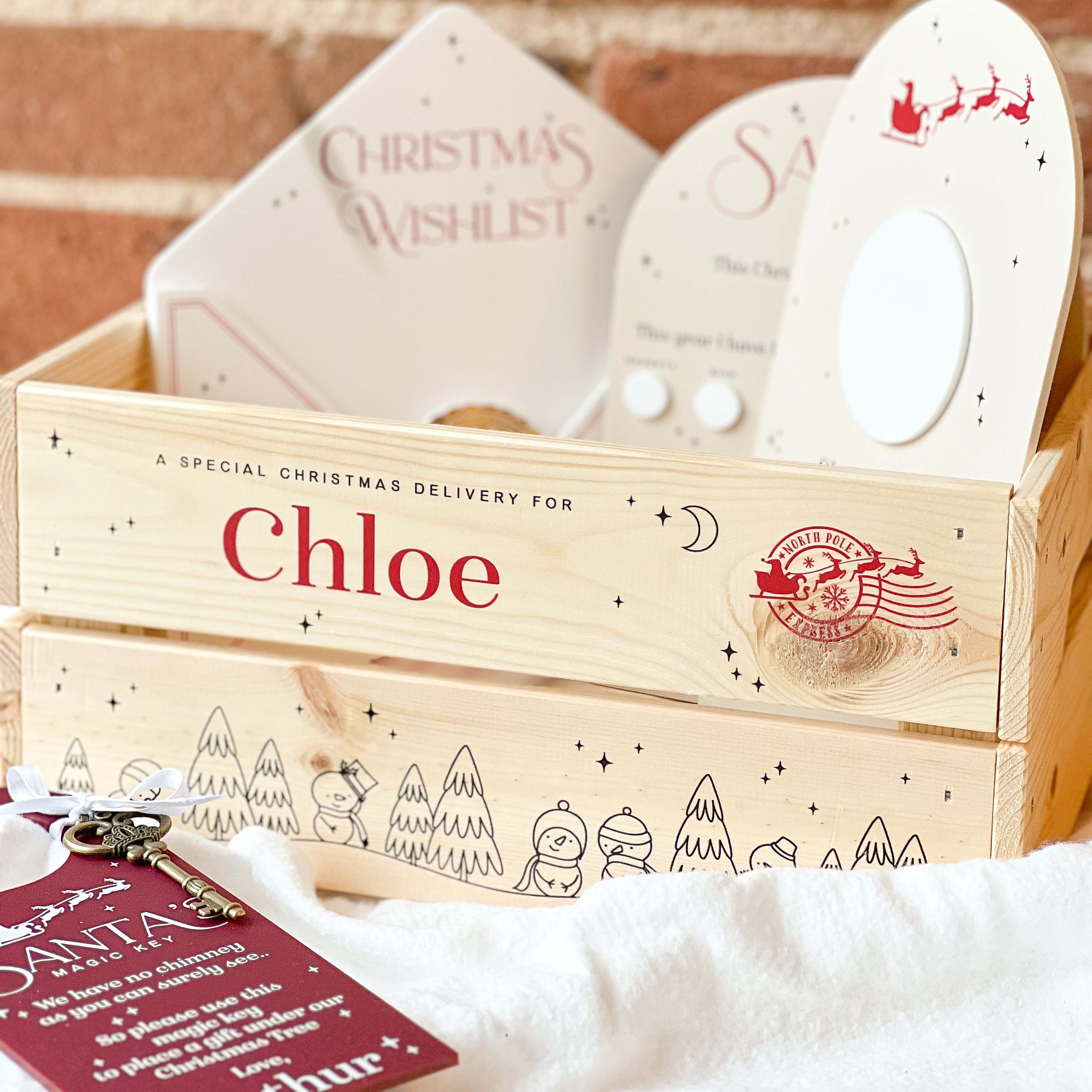Wooden Christmas Eve gift box with personalised name 'Chloe' and Christmas-themed items on a soft surface.