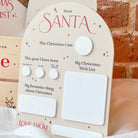Children's letter to Santa with buttons and space for writing, against a brick wall background.