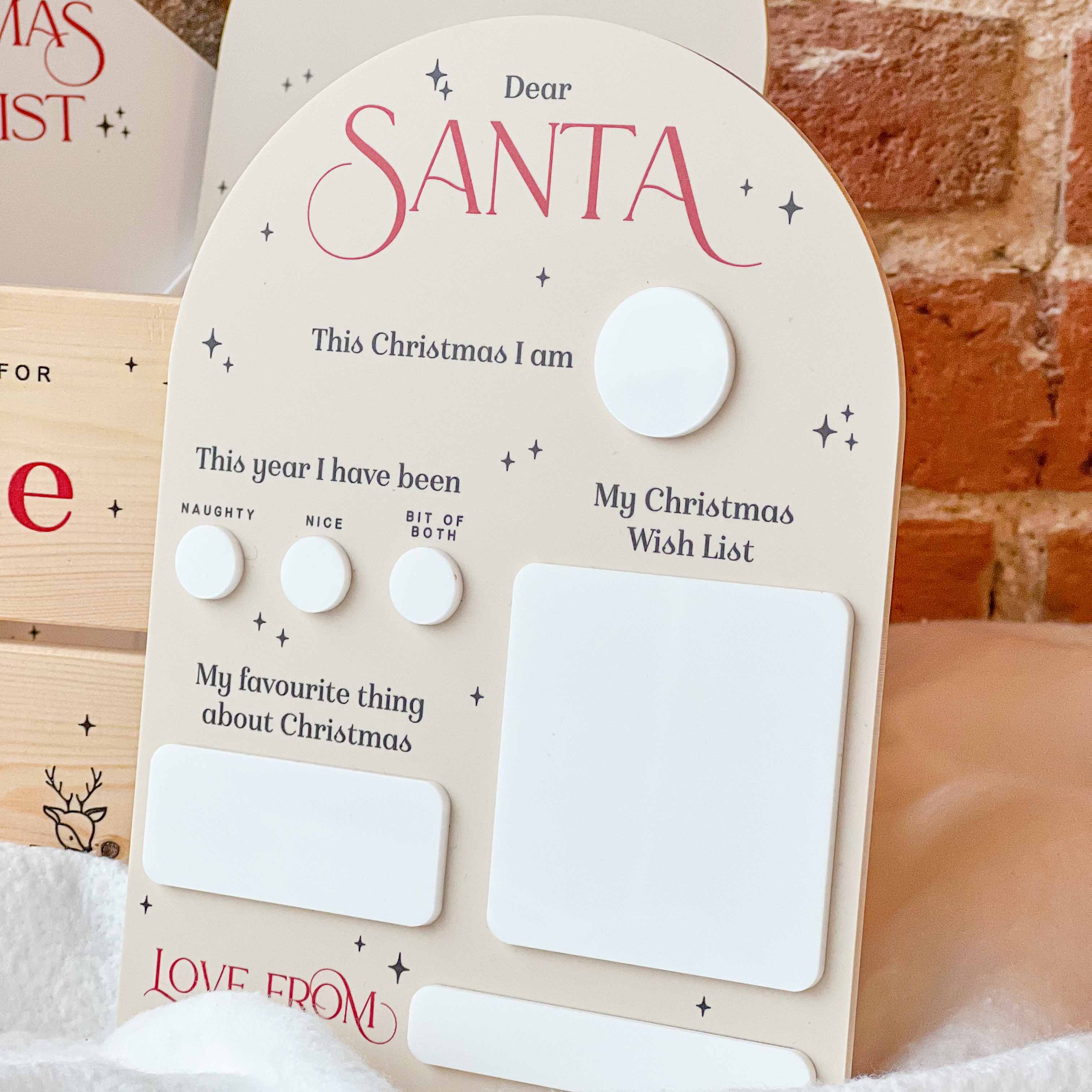 Children's letter to Santa with buttons and space for writing, against a brick wall background.