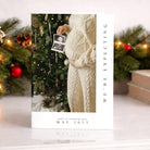 Pregnant person holding an ultrasound photo with Christmas tree in the background