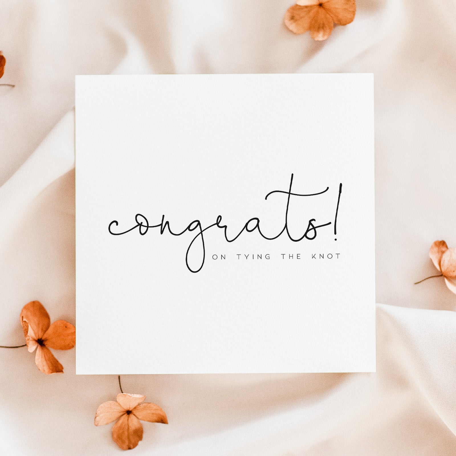 White card with 'congrats! on tying the knot' text surrounded by orange flowers on a beige background