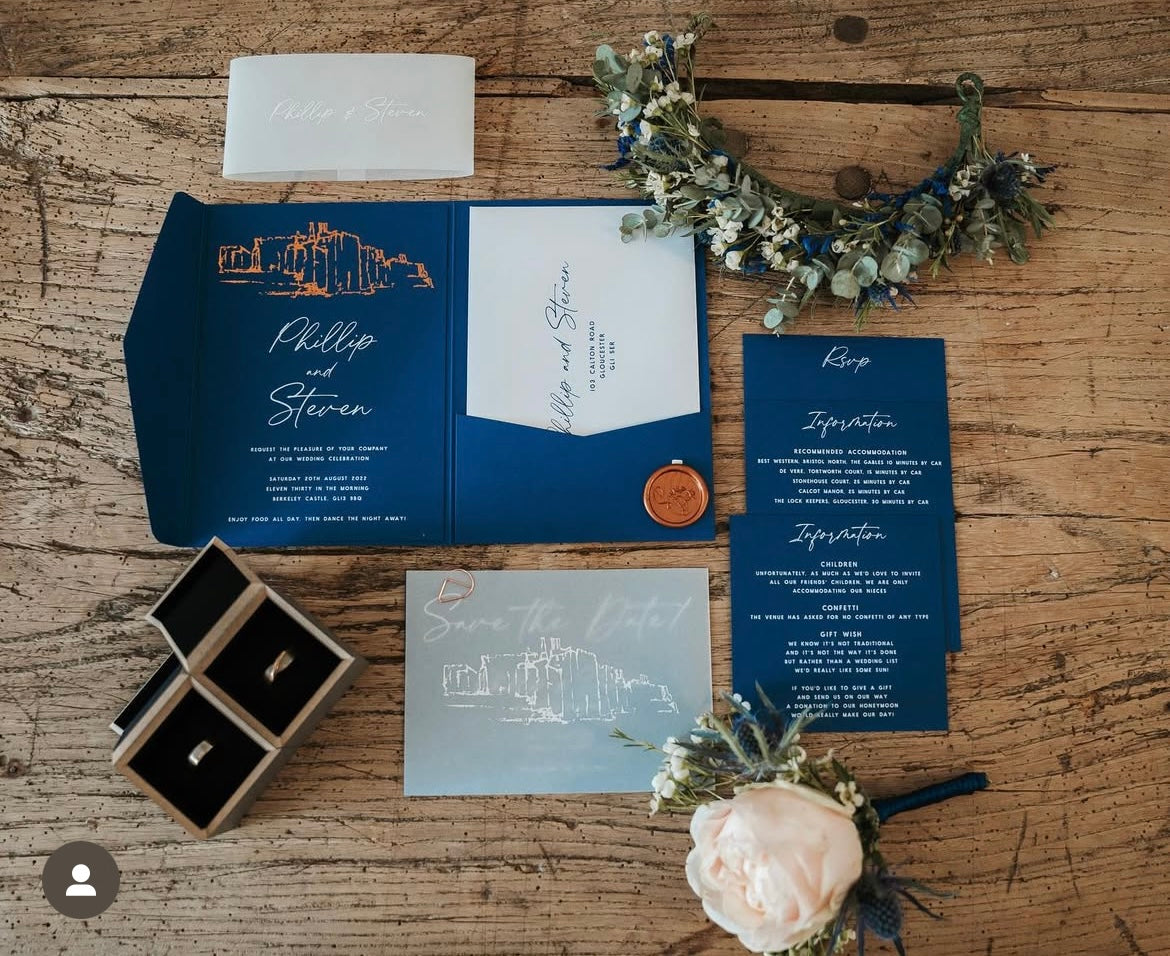Wedding invitation set with navy blue envelope, card, and details on a wooden surface.