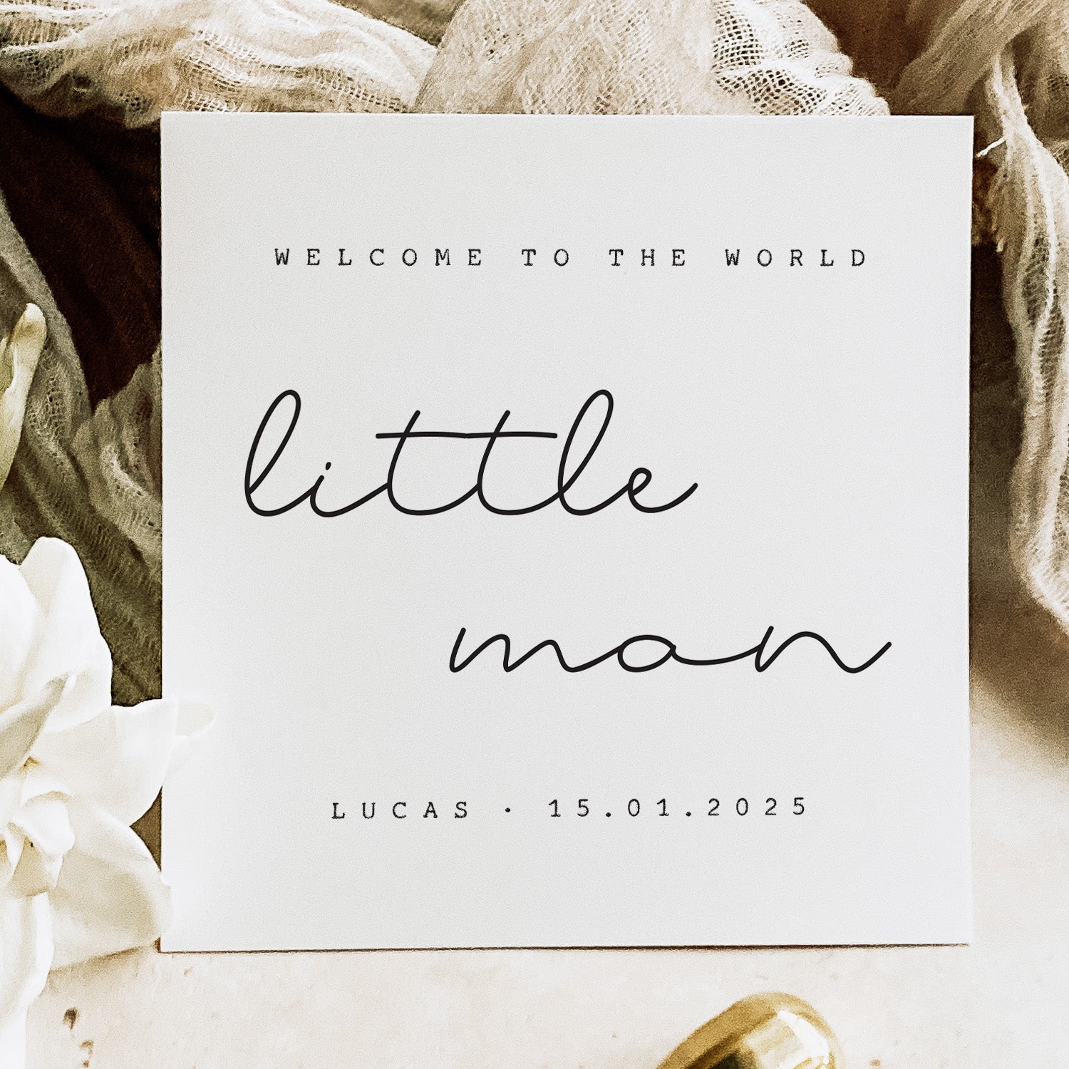 new baby card with 'Welcome to the world little man' text on a soft fabric background.