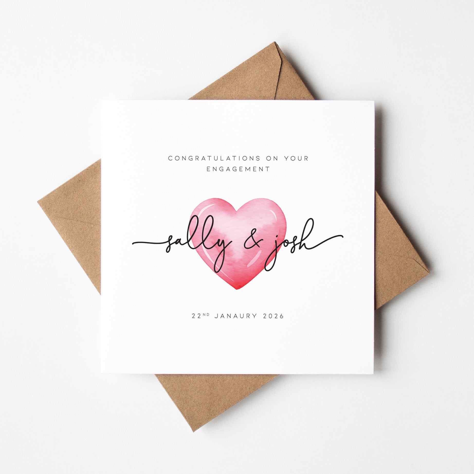 Engagement card with pink heart and names 'sally & josh' on a white background with brown envelope.