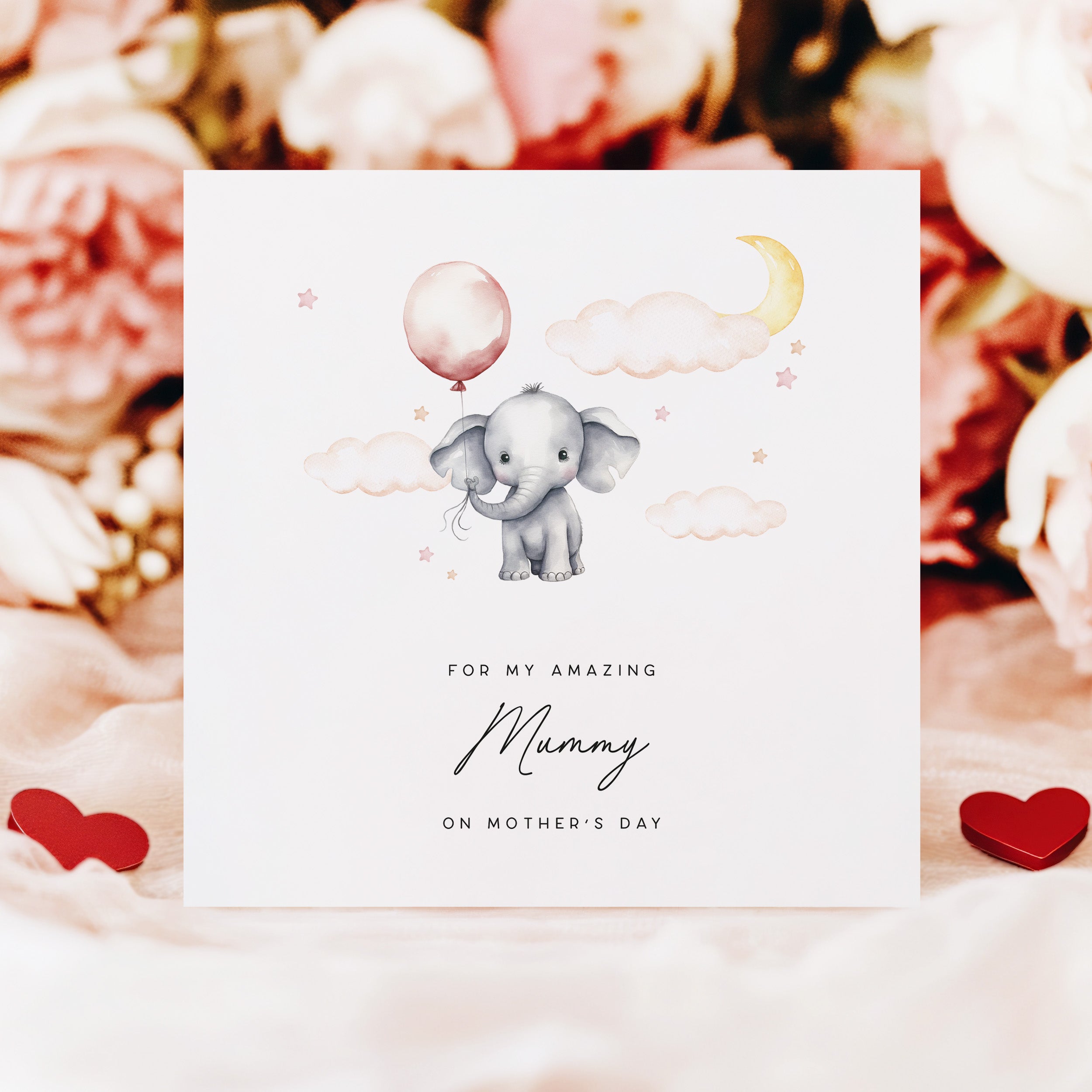 Greeting card with an elephant holding a balloon, surrounded by flowers and hearts.